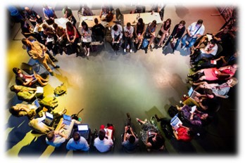 A colorful circle of seated people with laptops and notebooks